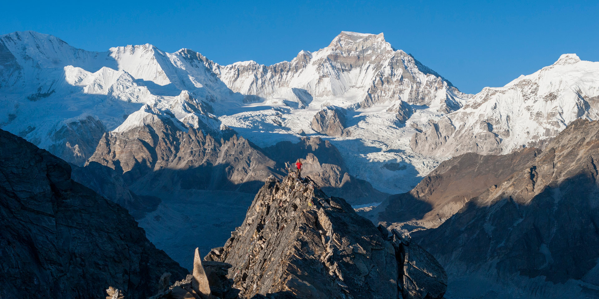 Trekker on top of Gokyo Ri with Mt Gyachung Kyang the worlds 15th highest mountain in the background